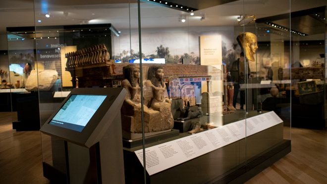 A digital label about Alexander Henry Rhind located next to a case featuring objects from the Rhind Tomb.